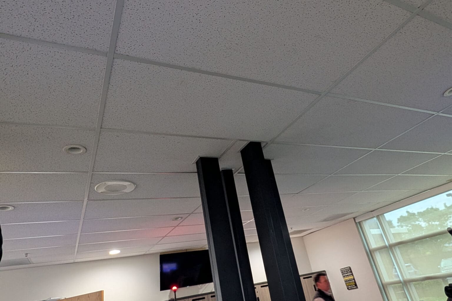 Office ceiling with lights and pillars visible.