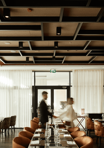 Modern restaurant interior with two blurred figures.